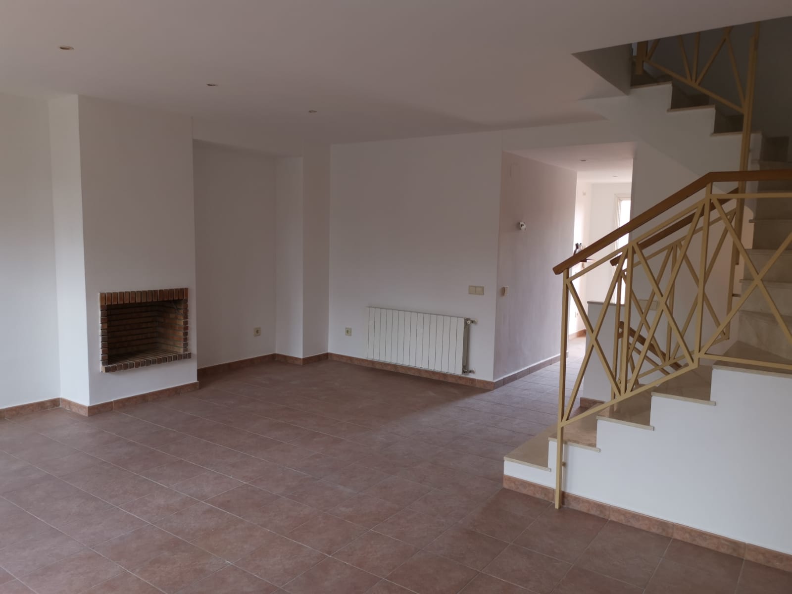 Living room with a brick fireplace and staircase (provisional photo).