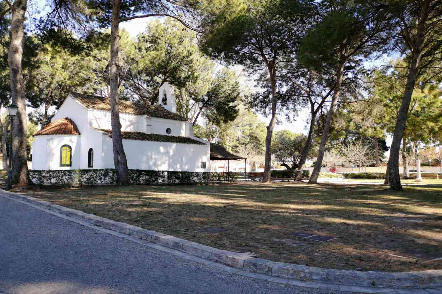 The whitewashed hermitage chapel of Campolivar set among tall pine trees.